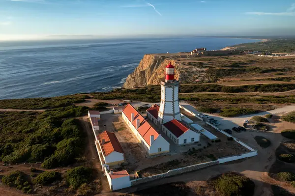 Cabo Espichel 'deki deniz fenerinin ya da Cape Espichel' in günbatımındaki güzel insansız hava aracı manzarası. Atlantik Okyanusu kıyısı, Sesimbra, Portekiz. Deniz kıyıları, yüksek uçurumlar, Portekiz mimarisi, günbatımı yaz manzarası, mavi