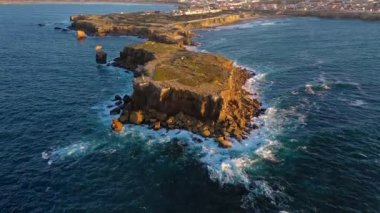 İnsansız hava aracı günbatımında yüksek uçurumlara ve deniz dalgalarına doğru uçar. Okyanus dalgalarının en yüksek görüntüsü kayalık kıyılarda kırılır ve içeri çekilir. Yaz günbatımı sisi, büyük taşlar, insanların manzaranın tadını çıkarması.