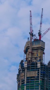 Gündüz bulutlu gökyüzünde yüksek katlı inşaat alanının dikey zaman çizelgesi. Dramatik bulutlar hızlı uçar, modern teknoloji, gökdelen inşaatı, vinçler hareket eder, gündüz vakti, endüstriyel konsept, şehirleşme