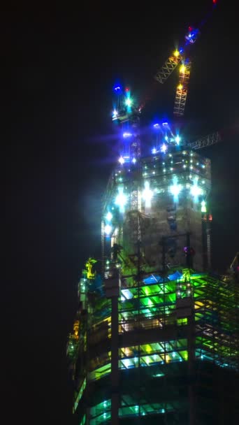 高層建築現場での実用的な夜間スケジュール クローズアップ モダンなコンドーム オフィスビル クレーンが動き 点灯します 超高層エンジニアリング クレーン移動 — ストック動画