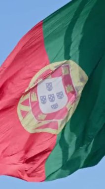 Close view of big national flag of Portugal waving in the wind from right to left on a clear sunny day at blue sky. Patriotism, democracy, politics, nation, European union member country. Selective