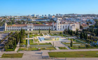 Jeronimos Manastırı ve Santa Maria de Belem Kilisesi 'nin havadan görünüşü ve açık mavi gökyüzü ile güneşli bir günde Lizbon, Portekiz' in merkezinde taze yeşillik ve büyük bir çeşme ile Empire Square Garden. UNESCO