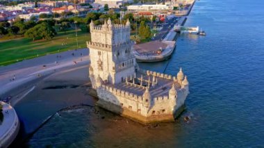 Belem Kulesi 'nin havadan görünüşü, Lizbon, Portekiz' in ünlü simgesi ve güneşli bir günde Tagus Nehri 'nin kıyısında turistik bir yer, açık mavi gökyüzü ve bulutsuz. Drone dışarı taşır ve eski 16 'nın görüntüsünü yukarı kaldırır.