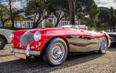 Lizbon, Portekiz - 20 Ocak 2024: 2 tonluk Reno kırmızısı ve siyah Austin-Healey 100 model üstü açık spor araba kaldırım yolunda park edilmiş. Kırmızı kadife ve deri, tahta direksiyon, katla