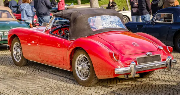 stock image Lisbon, Portugal - Jan 20, 2024: Rear view of classic red MGA sports car with drophead up parked on a cobblestone road near green park. 