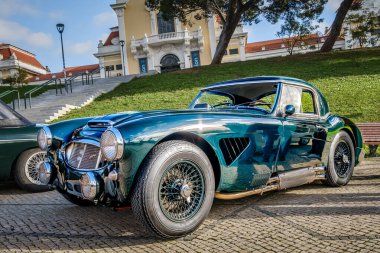 Lizbon, Portekiz - 20 Ocak 2024: Yeşil parkın yanındaki kaldırım taşında yeşil Austin Healey 3000 model spor araba. Austin-Healey BMC 'den 2 kapılı iki koltuklu roadster.