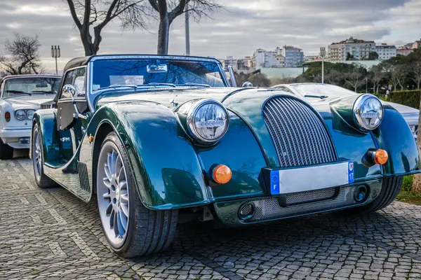 stock image Lisbon, Portugal - Jan 20, 2024: A classic dark green Morgan Plus 6 sports car with chrome detailing parked on a cobblestone path near green park. 