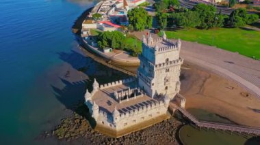 Belem Kulesi 'nin havadan görünüşü, Lizbon, Portekiz' in ünlü simgesi ve güneşli bir günde Tagus Nehri 'nin kıyısında turistik bir yer, açık mavi gökyüzü ve bulutsuz. İnsansız hava aracı 16. yüzyıla doğru ve üzerinde uçar.