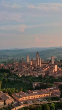Havadan yükselen insansız hava aracı görüntüsü ya da şafak vakti Toskana, Toskana bölgesindeki San Gimignano 'nun ünlü kulelerine doğru uçmak, bir UNESCO miras alanı olan ortaçağ İtalyan gökdelenleri şehri. Alçak güneş