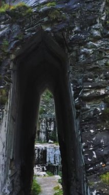 İHA 'nın havadan görüntüsü, İtalya' nın Carrara kentindeki terk edilmiş mermer ocağının yüksek kayasının önünde yükseliyor. Yağmurdan sonra parlak güneş ışığına karşı kurumuş kaya ve endüstriyel atıklar. Güneş ışınları