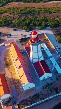 Cabo Espichel ya da Cape Espichel 'deki deniz fenerinin gün batımında uçan insansız hava aracı görüntüsü. Atlantik Okyanusu kıyısı, Sesimbra, Portekiz. Uç, parallax, yüksek uçurumlar, Portekiz mimarisi, günbatımı yazı