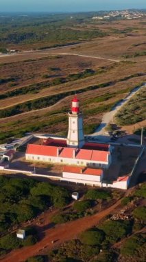 Cabo Espichel ya da Cape Espichel 'deki deniz fenerinin günbatımında yörünge drone görüntüsü. Atlantik Okyanusu kıyısı, Sesimbra, Portekiz. Uç, parallax, yüksek uçurumlar, Portekiz mimarisi, günbatımı yazı