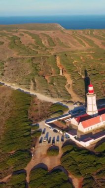 Güneş batarken Cabo Espichel ya da Cape Espichel 'deki deniz fenerinin insansız hava aracı görüntüsüne yaklaş. Atlantik Okyanusu kıyısı, Sesimbra, Portekiz. Yaklaş, doli, yüksek uçurumlar, Portekiz mimarisi