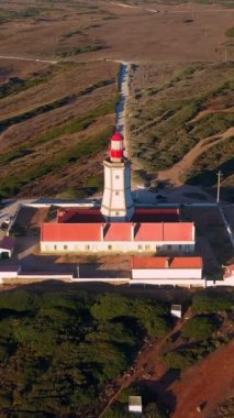 İnsansız hava aracı, güneş batarken Cabo Espichel veya Cape Espichel 'deki deniz fenerinin üzerinden geçer. Atlantik Okyanusu kıyısı, Sesimbra, Portekiz. Atış yapmak, yaklaşmak, uçmak, yüksek uçurumlar, Portekiz mimarisi.
