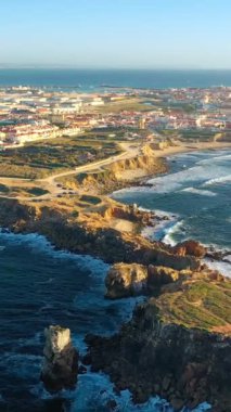 İnsansız hava aracı Peniche adası ve Portekiz 'in üzerinde akşam güneşinde okyanus dalgaları kayalık kayalıklara vurur. Yüksek uçurum yarımadasındaki güzel balıkçı kasabasının havasını yakınlaştır. Dolly ortaya çıkıyor