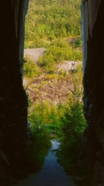 İnsansız hava aracı, terk edilmiş mermer ocağının kaya kesimli girişinden ve Apuan Alps dağları, Carrara, Toskana, İtalya 'nın yüksek ormanlık yamaçlarına uçuyor. Yaş ve eskimiş kayalar, yemyeşil yapraklar.