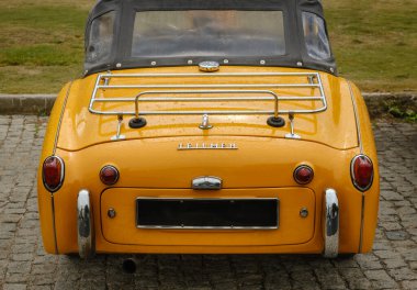 Lisbon, Portugal - Oct 15, 2023: Rear and high angle view of yellow convertible Triumph TR3A soft top drophead car on a driveway. Vintage car with rounded headlights and classic styling, Triumph Motor clipart