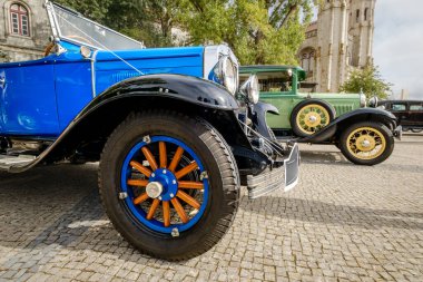 Lizbon, Portekiz - 15 Ekim 2023: Eşsiz Chevrolet 1929 AC International, güneşli bir günde tarihi binanın yakınındaki kaldırım taşlı yolda, klasik araba sahiplerinin yanında.