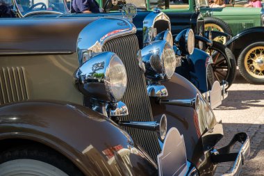 Lizbon, Portekiz - Sep 29, 2024: Plymouth DeLuxe 1934 'ün benzersiz yelkenli kaput süsü, parlak krom ızgara ve şehir ortamında büyük farlarla yakın çekim ve seçici odak noktası. Plymouth