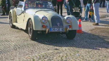 Lizbon, Portekiz - 20 Ocak 2024: Güneşli bir günde İngiliz araba sahipleri kulübü toplantısı sırasında arabalar yavaş yavaş geçiyor. İnsanlar, Morgan, MG, Ford ve diğerlerinin modern ve klasik araba geçit töreninden hoşlanıyorlar.