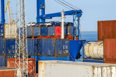 Kargo ve tank konteynırları güneşli bir günde deniz limanında yük taşıyıcı üzerinde arabalarla dolu. Deniz lojistiği, ulaşım, ticari liman, çeşitli renklerde nakliye konteynerleri, kargo