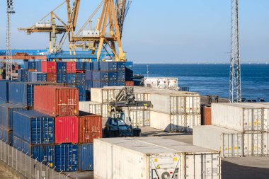 Maritime logistics and transportation scene at commercial seaport with stacked shipping containers, gantry and STS cranes, reach stackers in cargo terminal. International shipping and freight clipart