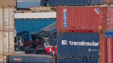 Mar 13, 2024 - Lizbon, Portekiz: Güneşli bir günde ticari liman terminalindeki yayıcı nakliye konteynırının yakın görüntüsü ve izleme görüntüsü. İş, lojistik, ithalat, ihracat