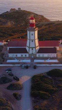 Gün batımında Cabo Espichel ya da Cape Espichel 'deki deniz fenerinin insansız hava aracı görüntüsüne yaklaşıyoruz. Atlantik Okyanusu kıyısı, Sesimbra, Portekiz. Çek, yakınlaştır, parallax, yüksek uçurumlar, Portekiz mimarisi