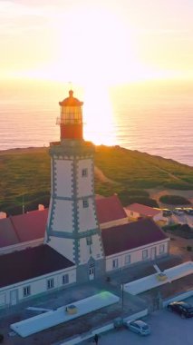 Gün batımında Cabo Espichel ya da Cape Espichel 'deki deniz fenerinin havadan görüntüsünü eğ. Atlantik Okyanusu kıyısı, Sesimbra, Portekiz. Aşağı inen, yüksek uçurumlar, Portekiz mimarisi, gün batımı yaz manzarası..