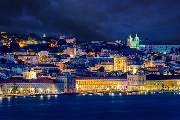 Çarpıcı gece gökyüzü altında ışıl ışıl şehir ışıkları olan Lizbon 'un tarihi kasabası. Praca do Comercio ya da Ticaret Meydanı ve ikonik simgeler Tagus nehrinin kıyısında, hava karardıktan sonra şehir, kiliseler ve