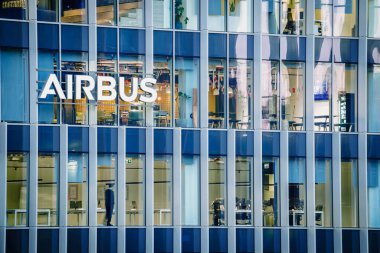 16 Ocak 2025 - Lizbon, Portekiz: Airbus ofis binasının ya da aydınlık logolu ve modern cam cepheli merkez binalarının gündüz manzarası. Çalışma alanının içinde masalarda insanlar, önde gelen havacılık şirketi, modern mimari, günlük şirket