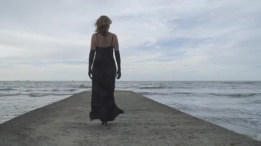 Sahildeki iskelede yürüyen zarif bir kadının arkası. Yaz tatili konsepti.