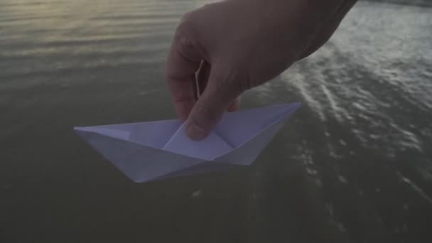 手将纸船抛入水中 美丽的夏日夕阳西下的大海和折纸船 — 图库视频影像