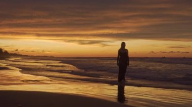 Genç mutlu romantik kız gün batımında sahilde yürüyor. Tam boy. Arka plan.
