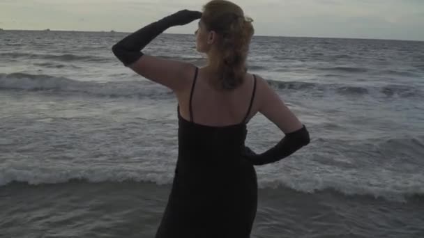 Μοντέλο Ένα Μακρύ Μαύρο Φόρεμα Στην Προβλήτα Παραθαλάσσιο Ποζάροντας Πάνω — Αρχείο Βίντεο