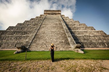 Meksika, Yucatan 'daki Chichen-Itza piramidinin önünde şapka ve siyah elbise giyen bir kadın.