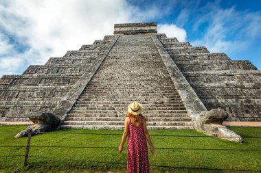 Meksika, Yucatan 'daki Chichen-Itza piramidinin önünde şapka ve kırmızı elbise giyen kadın.