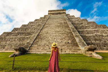 Meksika, Yucatan 'daki Chichen-Itza piramidinin önünde şapka ve kırmızı elbise giyen kadın.