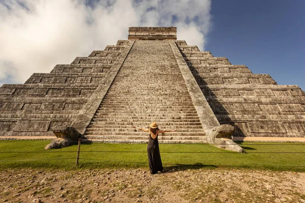 Meksika, Yucatan 'daki Chichen-Itza piramidinin önünde şapka ve siyah elbise giyen bir kadın.