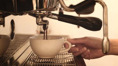 Barista preparing cup of coffee in coffee machine, woman'd hand holding the cup of coffee