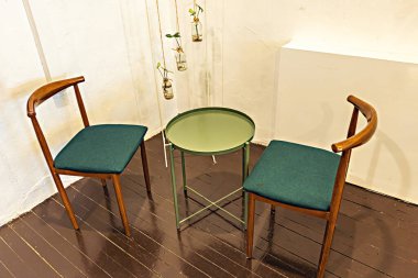 Cafe minimalistic interior green table and chairs with hanging plants against white wall