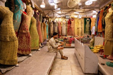 Pakistani man selling colorful fabric and dresses on the Qissa Khwani Bazaar in Peshawar, Pakistan