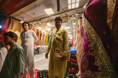 Pakistani man selling colorful fabric and dresses on the Qissa Khwani Bazaar in Peshawar, Pakistan