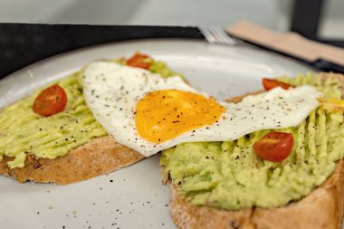 Classical breakfast close up toasts with avocado and sunny side egg