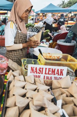 Malezya 'da gece pazarında Nasi Lemak (çeviri: hindistan cevizi pilavı) satan genç Malezyalı kadın