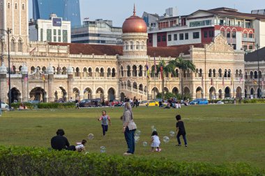 Malezyalı aile Kuala Lumpur Malezya 'daki Merdeka Meydanı' nda yeşil çimlerde oynuyor