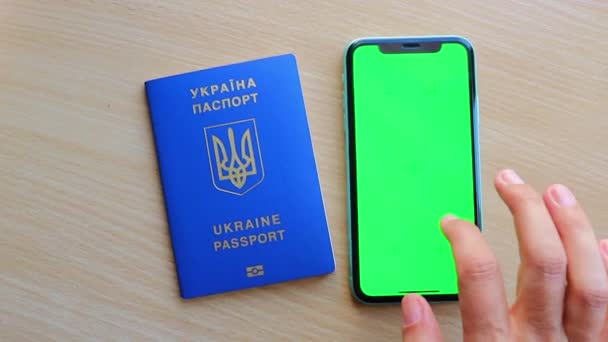 緑の画面閲覧クロマキーソーシャルメディアを読むウクライナのパスポートとノートブックとテーブルの上に閉じる — ストック動画