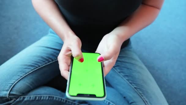 Iphoneの緑の画面をスクロールジーンズを身に着けている女の子クロマキーの閲覧ニュースを読む閉じる手 — ストック動画