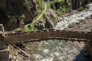 Pakistan 'ın kuzeyindeki Kalash vadisinde nehrin üzerindeki tahta köprü.