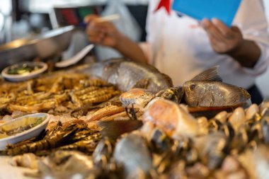 Deniz ürünleri restoranında aşçı çeşitli deniz ürünleri sunuyor.
